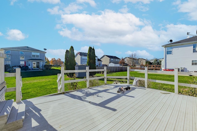 wooden deck with an outdoor fire pit, fence, a residential view, and a lawn