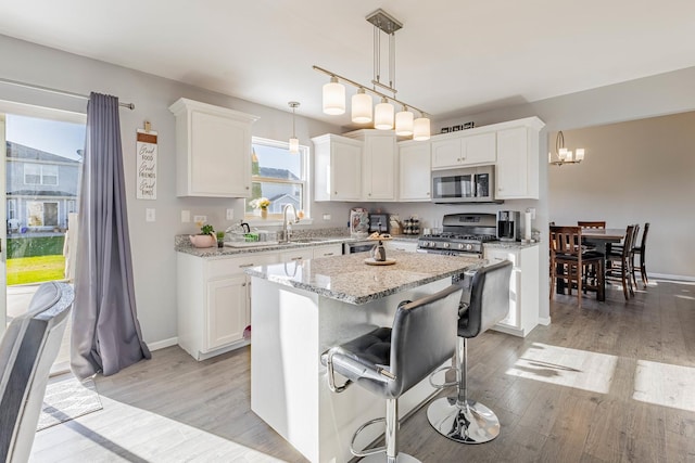kitchen featuring light wood-type flooring, appliances with stainless steel finishes, a center island, and white cabinets