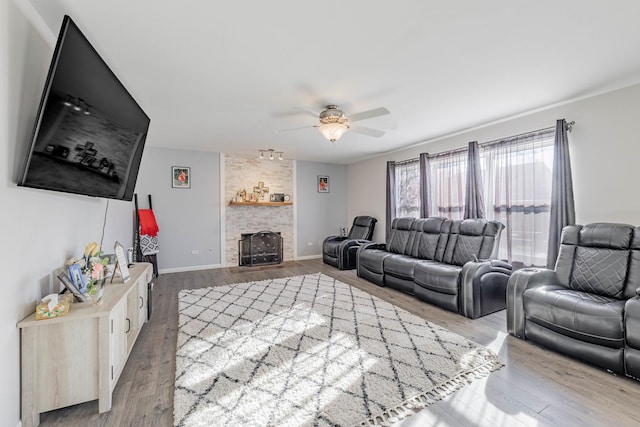 living area with ceiling fan, baseboards, wood finished floors, and a fireplace