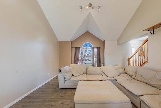 living area featuring wood finished floors, baseboards, vaulted ceiling, and stairs