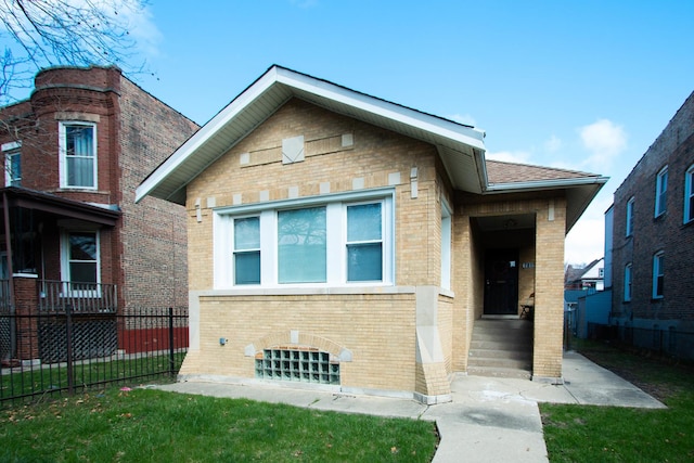 view of front of property with a front yard, brick siding, and fence