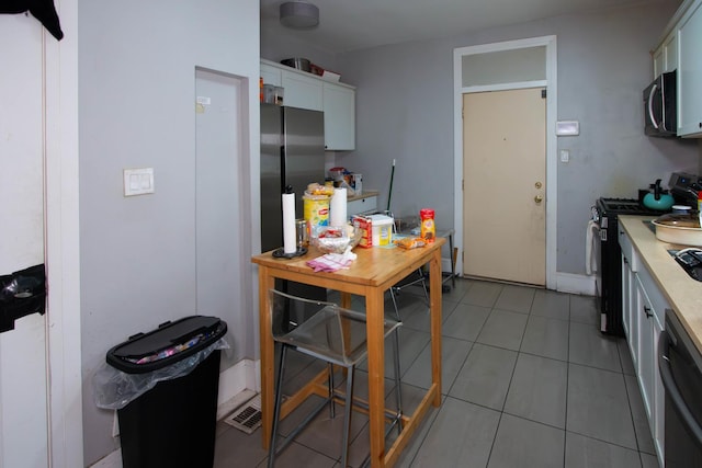 kitchen featuring stainless steel appliances, white cabinets, light countertops, and light tile patterned flooring
