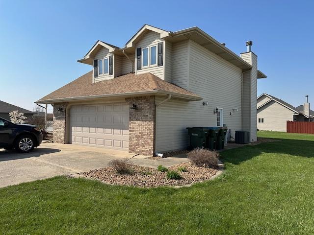 110 E Spring Rd, Coal City, IL 60416 - view of side of property with a garage, cooling unit, a yard, brick siding, and concrete driveway