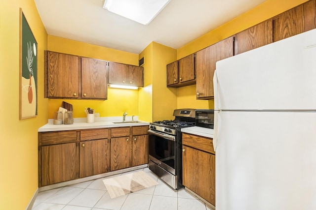 kitchen featuring freestanding refrigerator, black microwave, gas range, light countertops, and a sink