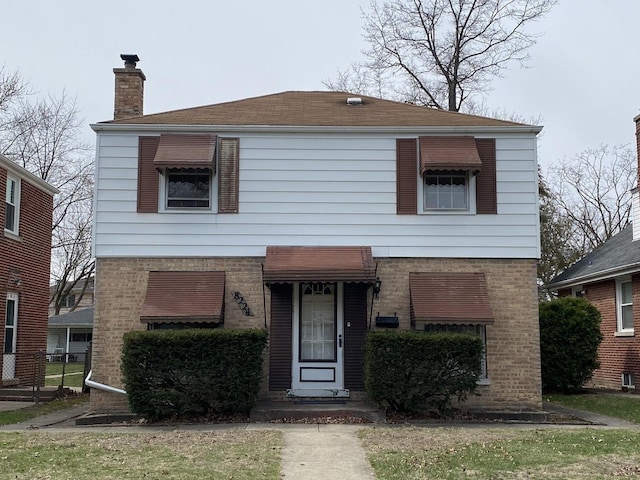 view of front facade featuring a chimney and brick siding