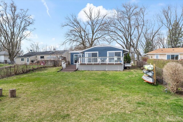 rear view of property featuring a fenced backyard, a wooden deck, and a yard