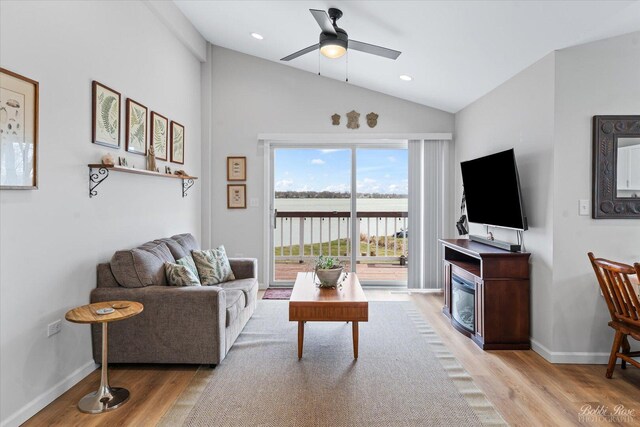 living room with light wood-style floors, baseboards, ceiling fan, and vaulted ceiling
