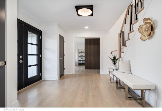 entryway featuring baseboards, light wood-style floors, crown molding, recessed lighting, and stairs