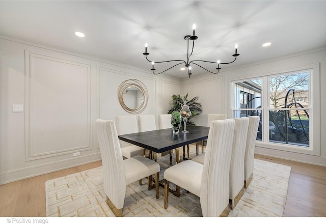 dining area with a decorative wall, a chandelier, crown molding, recessed lighting, and light wood finished floors
