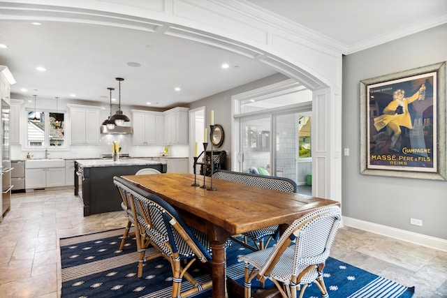 dining space with crown molding, arched walkways, stone finish floor, recessed lighting, and baseboards