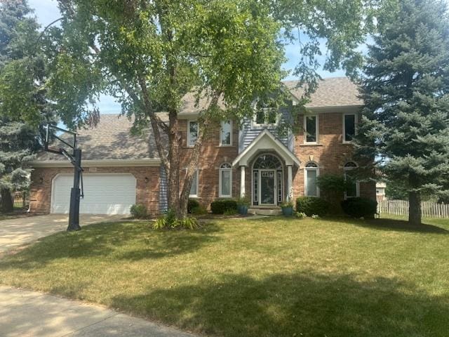 colonial home featuring an attached garage, fence, driveway, and a front lawn