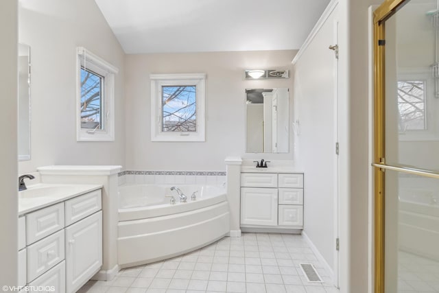 bathroom with a garden tub, visible vents, tile patterned floors, two vanities, and a sink