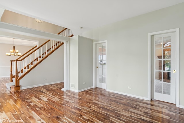 unfurnished living room featuring stairs, a chandelier, and wood finished floors