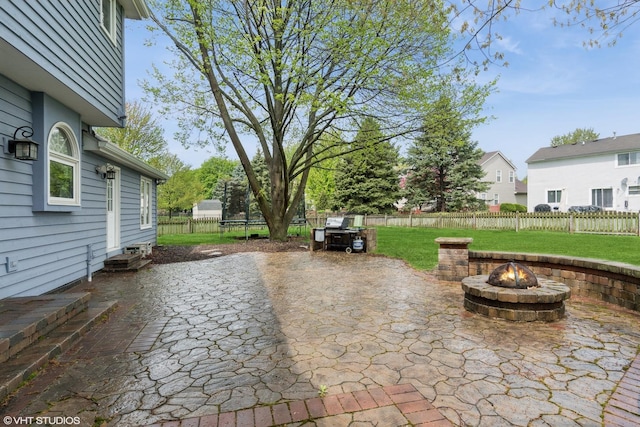 view of patio with a fenced backyard, a trampoline, and an outdoor fire pit