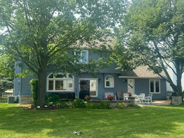 back of property featuring a lawn and central AC