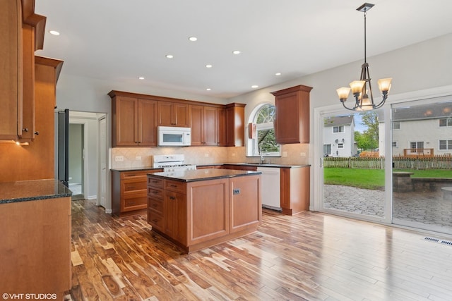 kitchen with white appliances, visible vents, decorative backsplash, and a sink
