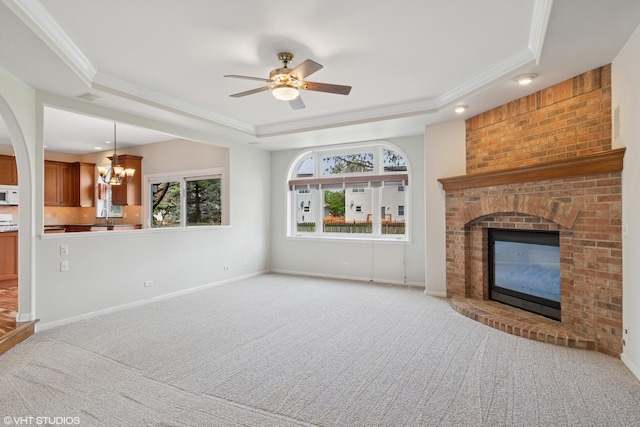 unfurnished living room with ornamental molding, a raised ceiling, a brick fireplace, and carpet flooring