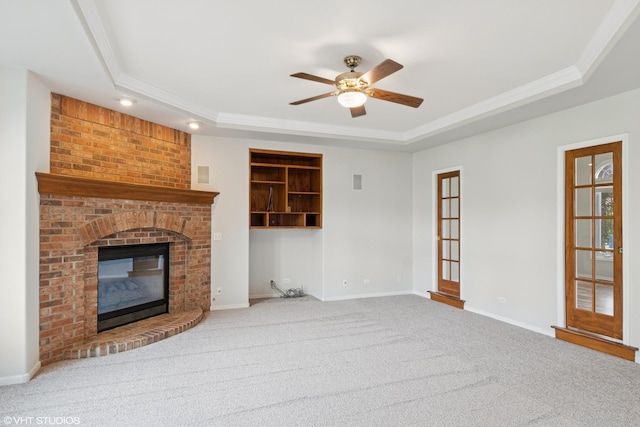 unfurnished living room featuring carpet floors, a tray ceiling, crown molding, and ceiling fan