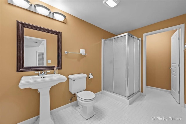 bathroom featuring toilet, baseboards, and a stall shower