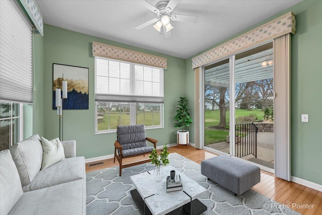 living area with wood finished floors, ceiling fan, baseboards, and visible vents