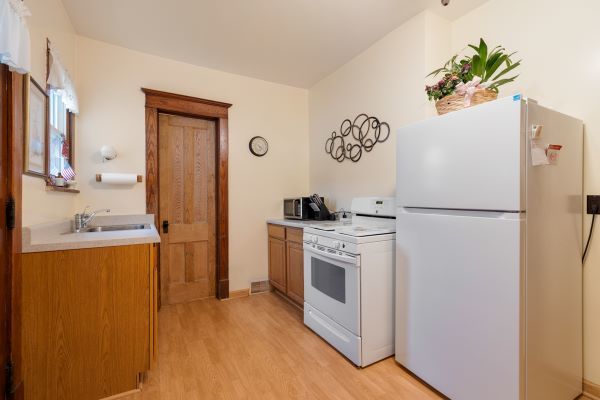 kitchen with white appliances, light countertops, a sink, brown cabinets, and light wood finished floors