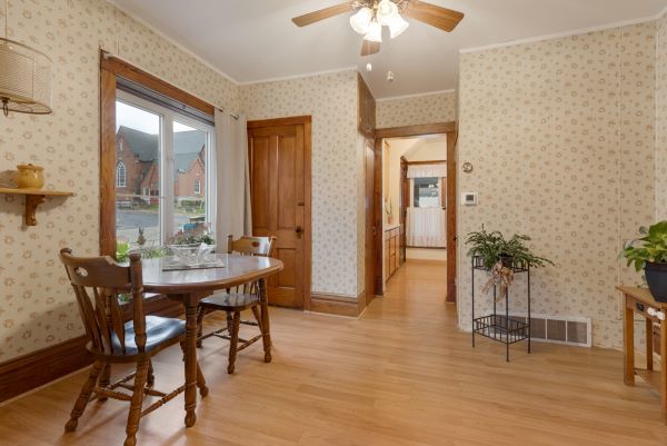 dining room featuring ornamental molding, ceiling fan, light wood-style floors, and wallpapered walls
