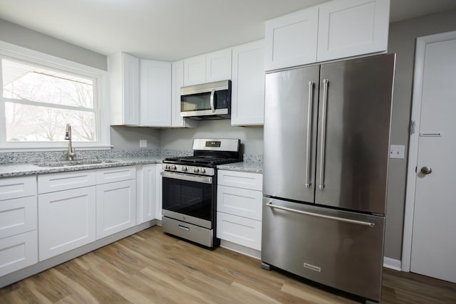 13 Park Pl, Kankakee, IL 60901 - kitchen featuring stainless steel appliances, light wood-style flooring, white cabinetry, and a sink