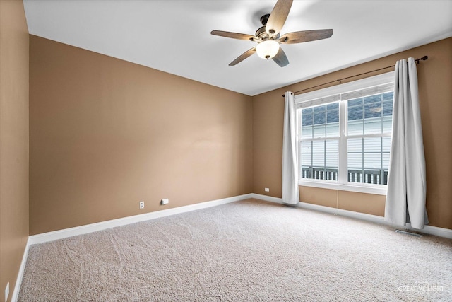 carpeted spare room featuring a ceiling fan and baseboards