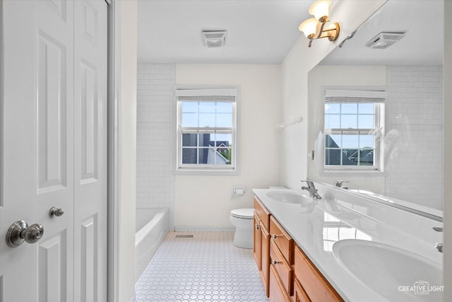 full bath with plenty of natural light, a closet, double vanity, and baseboards
