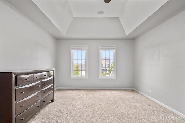 unfurnished bedroom with a tray ceiling, carpet flooring, and baseboards