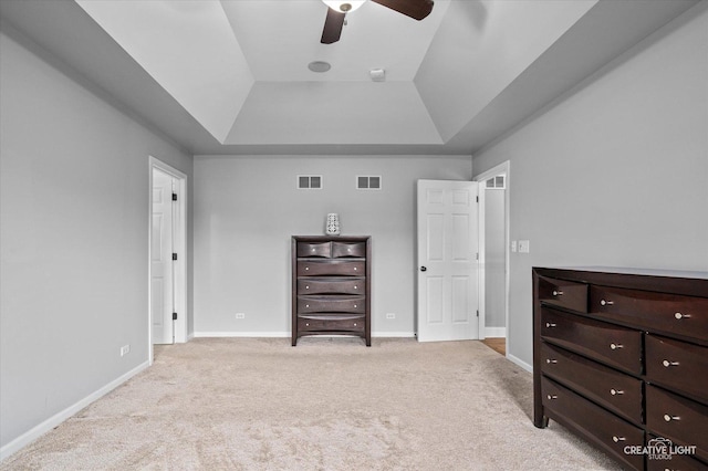 bedroom with a tray ceiling, light carpet, baseboards, and a ceiling fan