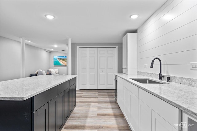 kitchen with a sink, light wood-style flooring, dark cabinetry, recessed lighting, and a kitchen island