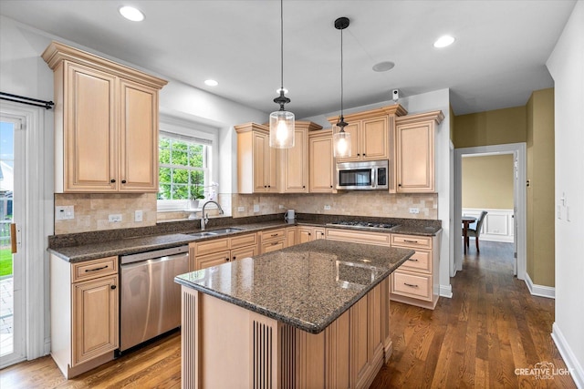 kitchen with stainless steel appliances, a sink, dark wood finished floors, decorative backsplash, and pendant lighting