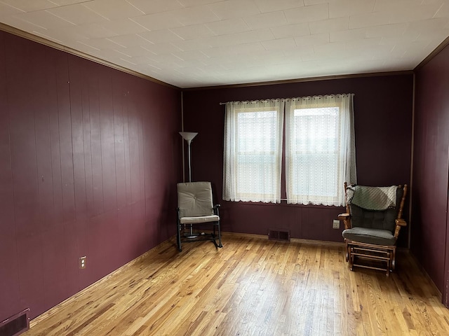 sitting room featuring wood finished floors, ornamental molding, and visible vents