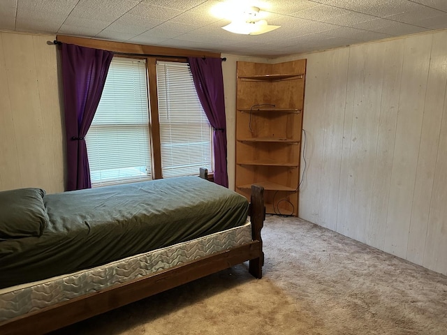 carpeted bedroom featuring wood walls