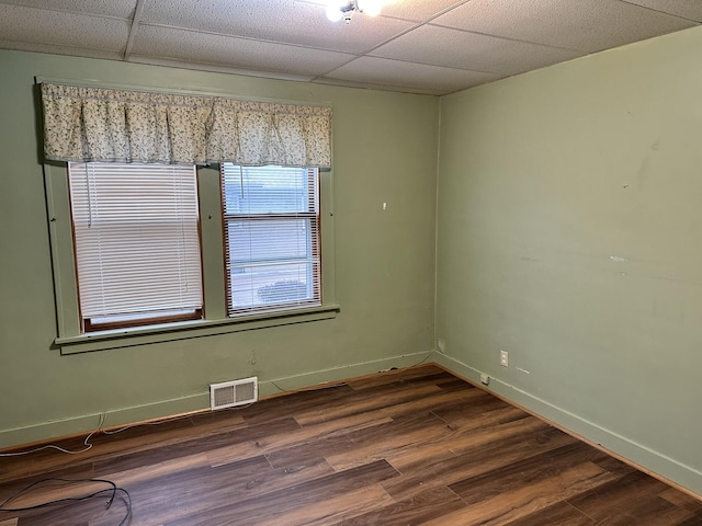 unfurnished room featuring visible vents, a drop ceiling, baseboards, and dark wood-style floors