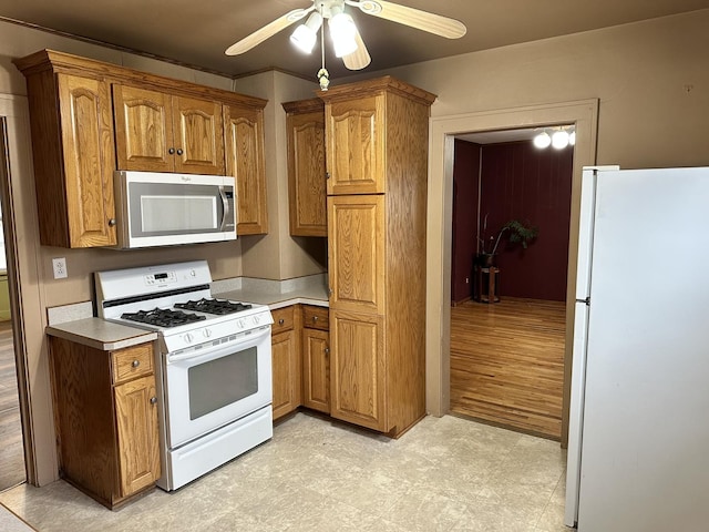 kitchen featuring a ceiling fan, brown cabinets, light countertops, and white appliances