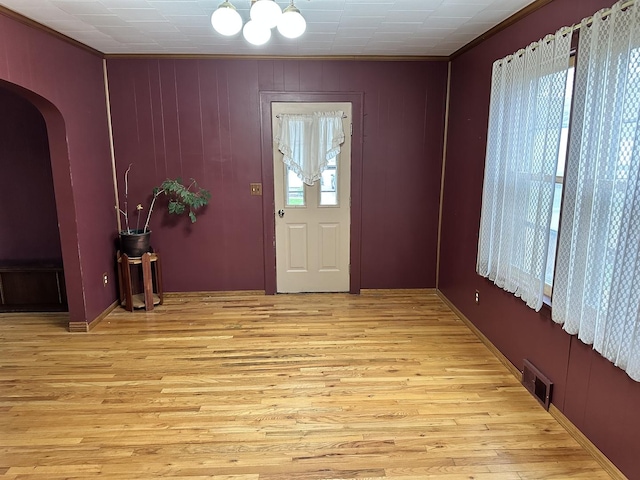 foyer with arched walkways, visible vents, and light wood-type flooring