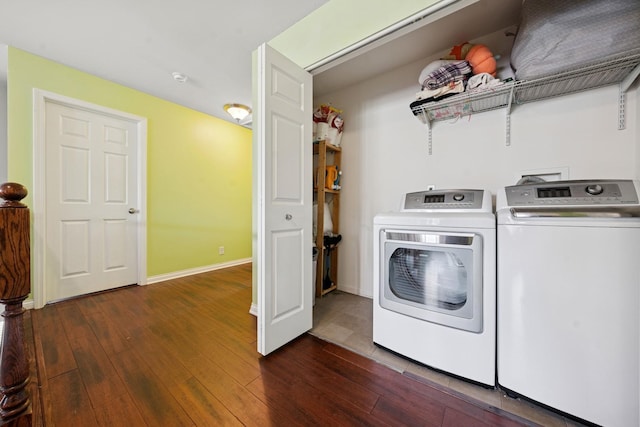 clothes washing area featuring baseboards, dark wood-type flooring, laundry area, and washer and clothes dryer
