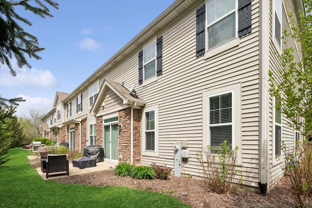 back of property with a yard, a patio area, and stone siding