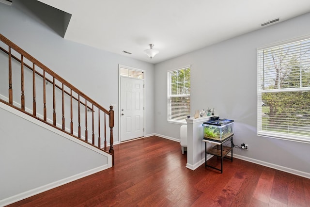 foyer entrance with baseboards, stairway, visible vents, and wood finished floors
