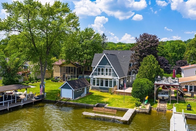 back of property featuring an outdoor structure, a water view, a yard, and a shingled roof