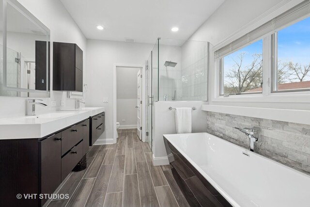 bathroom with double vanity, a freestanding tub, toilet, recessed lighting, and a shower stall