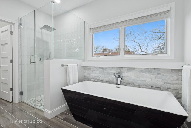 full bath featuring a soaking tub, a stall shower, and wood finished floors