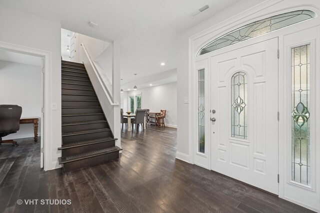 foyer entrance featuring visible vents, baseboards, dark wood-style flooring, and stairs