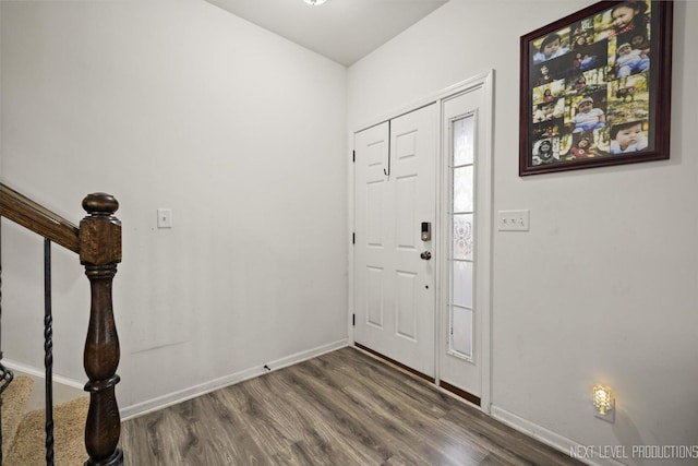 foyer entrance with dark wood-style flooring, baseboards, and stairs