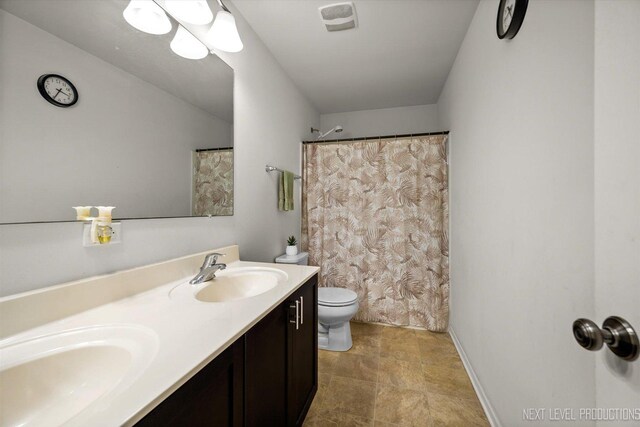 bathroom featuring a sink, visible vents, toilet, and double vanity