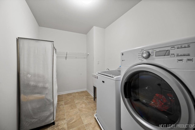 clothes washing area with baseboards and laundry area
