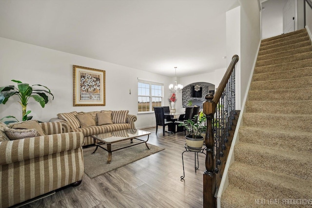 living room with stairs, a notable chandelier, and wood finished floors