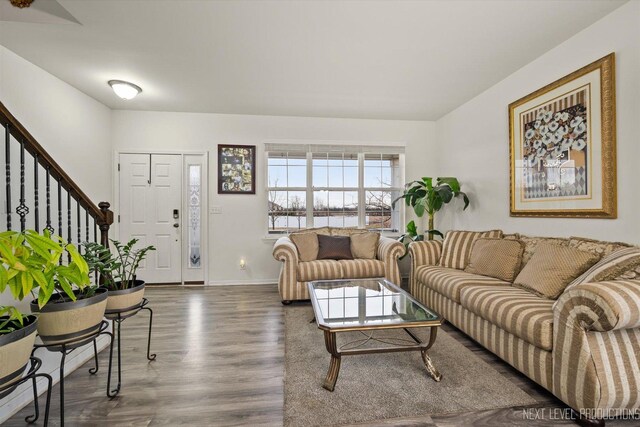 living area with baseboards, stairway, and wood finished floors